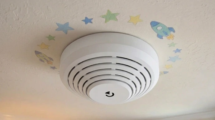 Ein Rauchmelder im Kinderzimmer mit dekorativer Tapete.