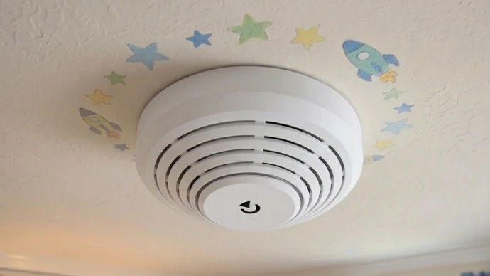 Ein Rauchmelder im Kinderzimmer mit dekorativer Tapete.
